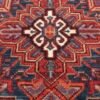 Detailed close-up of the central geometric medallion of a Heriz Persian rug, showing the thick wool pile and vibrant terracotta tones.