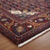 Macro view of a Persian Zanjan rug corner showing the geometric guard borders, robust edge binding, and authentic hand-finished fringe.