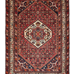 Full view of a 4' 11" x 6' 1" hand-knotted Persian Hamedan wool rug featuring a central geometric medallion on a vibrant madder red field.