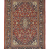 Full view of a 4' 8" x 6' 7" hand-knotted Persian Kashan rug with a large central floral medallion on a deep madder red field and navy borders.