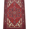 Full view of a 5' 3" x 6' 7" hand-knotted Persian Heriz rug featuring a large geometric star medallion on a rust-red and navy field.