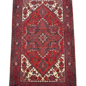 Full view of a 5' 3" x 6' 7" hand-knotted Persian Heriz rug featuring a large geometric star medallion on a rust-red and navy field.