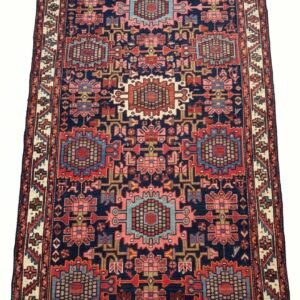 Full view of a 4' 7" x 6' 6" hand-knotted Persian Hamedan rug featuring a geometric central medallion on a madder red field with indigo borders.