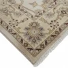 Detailed corner view of an Afghan Chobi rug showing the floral border, hand-bound edges, and short cream fringe.