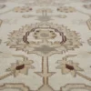 Macro shot of the hand-knotted wool pile and detailed floral vine patterns in cream and tan on an Afghan Chobi rug