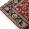 Detailed corner view of a red and navy Mashad wool rug showing the floral border patterns and clean white fringe.