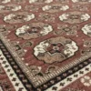 Macro shot showing the dense hand-knotted wool pile and an intricate octagonal floral medallion on a burgundy Indian rug.