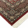 Detailed corner view of a red Indian wool rug showing the ornate border patterns and clean white hand-bound fringe.