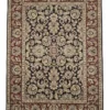 Full overhead view of a rectangular hand-knotted Indian wool rug with a rich red field and dense all-over ivory and blue floral patterns.