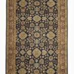 Full overhead view of a rectangular hand-knotted Indian wool rug with a deep navy blue field and repeating large tan floral medallions.