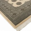 Detailed corner view of a Pakistan Bokhara rug showing the geometric border patterns, hand-bound edges, and clean white fringe.