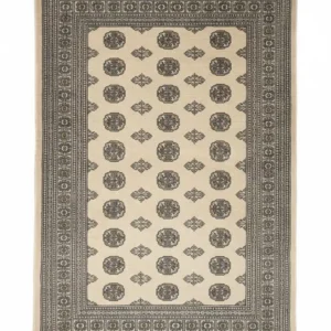 Full overhead view of a rectangular hand-knotted Pakistan Bokhara wool rug with a cream field and repeating charcoal and gold "elephant foot" medallions.