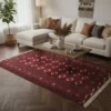 Modern living room with dark hardwood herringbone floors and a 4'7" x 6'6" burgundy Turkmen wool rug under a rustic wood coffee table.