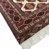 Detailed corner view of a Turkmen rug showing the complex geometric burgundy border and clean white hand-bound fringe.