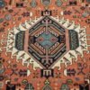 Close-up of the central geometric diamond medallion and tribal motifs on a hand-knotted Persian Gharacheh rug.