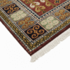 Detailed corner view of a red and blue Kazak rug showing the multi-colored square border patterns and white fringe.