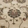 Close-up of the plush tufted wool pile and detailed green and tan floral motifs in the center of a neutral Indian rug.