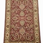 Full top-down view of a rectangular hand-tufted Indian wool rug featuring a deep red field with ornate cream and sage green floral patterns.