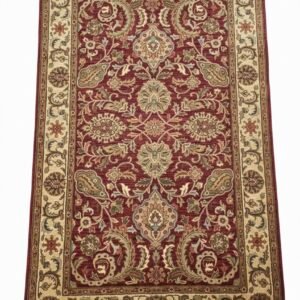 Full top-down view of a rectangular hand-tufted Indian wool rug featuring a deep red field with ornate cream and sage green floral patterns.