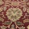 Close-up of the thick tufted wool pile and intricate floral embroidery-style details on a red Indian rug.