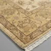 Detailed corner view of an ivory Afghan Chobi rug showing the wide ornate botanical border and short hand-bound wool fringe.