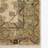 Detailed corner view of an ivory Afghan Chobi rug showing the wide sage-green floral border and short hand-bound wool fringe.