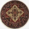 Full overhead view of a 6' x 6' circular hand-knotted Indian wool rug with a complex ivory and red star medallion on a dark navy and madder red field.