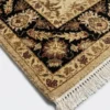 Detailed corner view of an ivory Indian rug showing the high-contrast black botanical border and clean white hand-bound fringe.