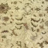 Macro shot of the dense hand-knotted wool pile on an ivory Indian rug showing detailed scrolling vines and floral patterns in gold and sage.