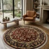 Bright modern living room with large windows and light wood floors, featuring a 6' x 6' round red Indian wool rug under a coffee table.