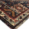 Detailed corner view of a red Persian Qashqai rug showing the multi-layered geometric border and hand-bound wool fringe.