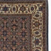 Detailed corner view of a rust-red India Mir rug showing the wide ivory geometric border and clean hand-bound white fringe.