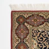 Detailed corner view of a Persian Kerman rug showing the multi-lobed floral border cartouches and clean white hand-bound fringe.