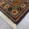 Detailed corner view of a Persian Koliai rug showing the wide olive-green geometric border and authentic hand-bound wool fringe.
