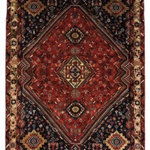 Full overhead view of a rectangular 5' 4" x 7' 3" hand-knotted Persian Qashqai wool rug with a large central diamond medallion on a rich red and navy field.