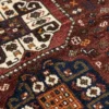 Macro shot of the central ivory and navy geometric medallion on a Persian Qashqai rug, showing dense hand-knotted wool and intricate symbols.