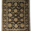 Full overhead view of a 6' x 9' 2" hand-knotted Indian wool rug with a black field and large-scale sage green and gold floral palmettes.