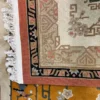 Close-up view of the underside of a gold Chinese wool rug, showing the visible individual hand-tied knots and authentic textile construction.