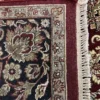 Close-up view of the underside of a red and beige Indian wool rug, showing individual hand-tied knots and authentic textile construction.