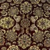 Macro shot of the dense hand-knotted wool pile showing intricate black and beige floral motifs on a deep red background.