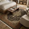 Bright modern bedroom with a wooden bed frame and neutral linens, featuring a 5' 11" x 8' 10" black and rust Indian medallion rug centered at the foot of the bed.