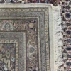 Close-up view of the underside of a brown and plum Indian wool rug, showing the visible individual hand-tied knots and authentic textile construction.