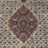 Macro shot of the dense hand-knotted wool pile showing the intricate Herati pattern and central plum and tobacco brown details.
