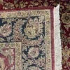 Close-up view of the underside of a red and gold Indian wool rug, showing the visible individual hand-tied knots and authentic textile construction.