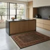 Modern kitchen with light wood cabinets and a black island, featuring a 5' x 6' 3" tobacco and rust Indian wool rug centered on the floor.