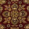 Macro shot of the dense hand-knotted wool pile showing intricate gold and sage floral motifs on a deep crimson background.