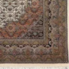 Detailed corner view of a square Indian wool rug showing the ornate sage and terracotta botanical border and clean ivory fringe.