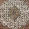 Macro shot of the dense hand-knotted wool pile showing the central diamond medallion with intricate sage, terracotta, and blue floral details.