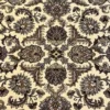 Macro shot of the dense hand-knotted wool pile showing intricate sage, tan, and dark brown floral motifs on a cream-ivory background.