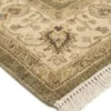 Detailed corner view of an olive Chobi rug showing the wide cream-tan botanical border and clean white hand-bound fringe.